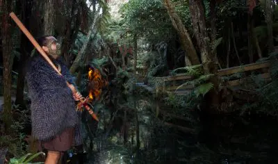 Experience an enchanting Māori Evening Dinner: traditional Māori attire, a serene forest stream, and authentic cultural hospitality.