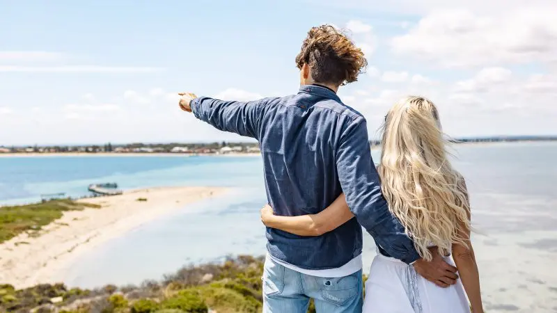 A couple stands by Margaret River’s scenic seaside as the man points at the ocean, ready for a thrilling wildlife adventure.