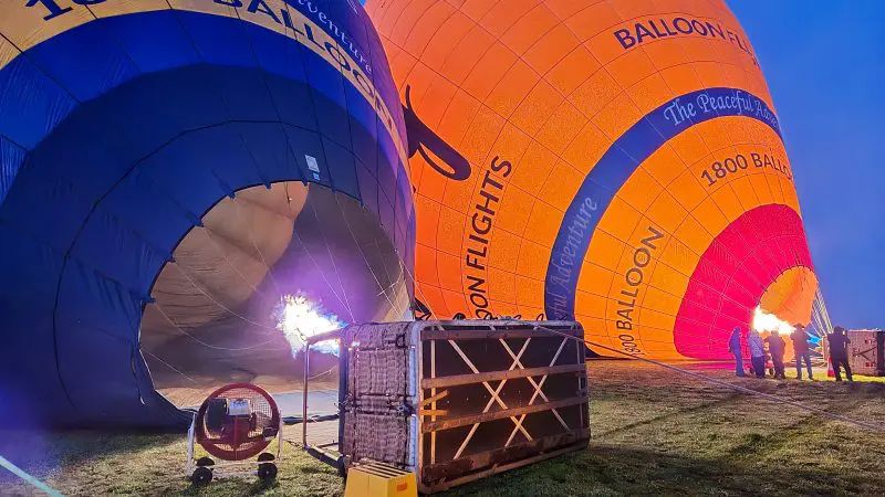 Vibrant hot air balloons inflating at sunrise in Perth Avon Valley, ready for scenic balloon flight with breakfast on grassy field.