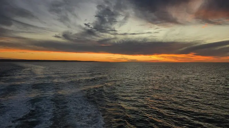 Breathtaking sunset over a calm ocean on Kangaroo Island 2-Day Wildlife Adventure, vibrant orange sky, dramatic clouds, scenic horizon.