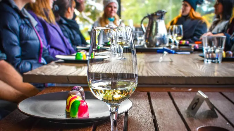 Premium white wine glass from a Coal River Valley Wine & Gin Safaris Private Day Tour, paired with gourmet chocolates and vibrant chats.