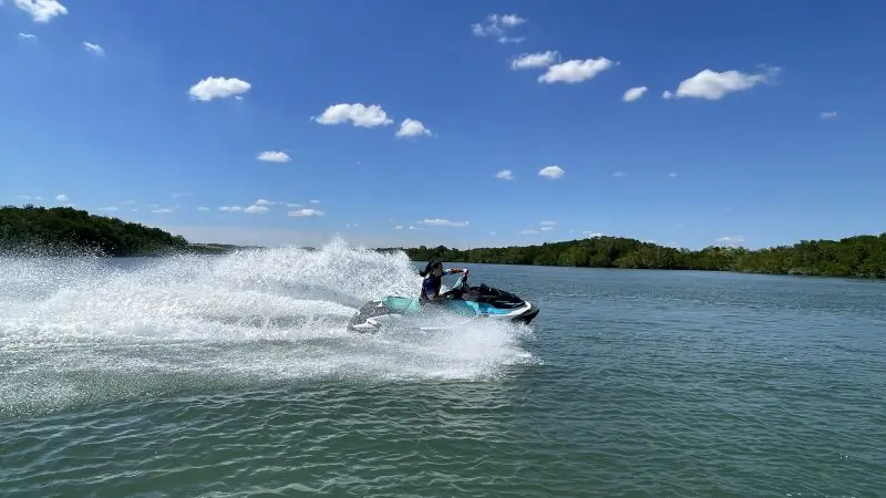 Jet ski enthusiast speeds down a sunlit river, racing towards the next Espresso Martini Tour destination on a clear, vibrant day.
