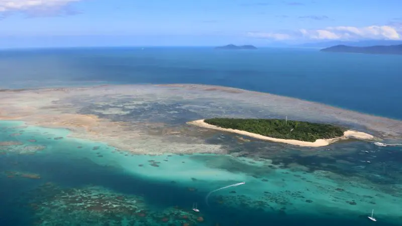 Stunning aerial shot of a lush tropical island, vibrant coral reefs, tour boats, and distant islands—ideal for Inner Reef Explorer tours.