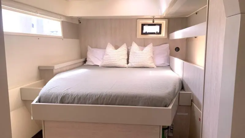 Inviting bed with plump white pillows, airy bedding, panoramic windows, and clever built-in storage in a Whitehaven Dreamer cabin.