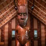 Intricately tattooed wooden Māori carving in a traditional meeting house at Waitangi Treaty Grounds, historic site in New Zealand.