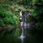 Thrilling bungee jumper plunges upside down above a scenic pond at Australia’s only bungy Skypark, lush greenery and waterfall views.