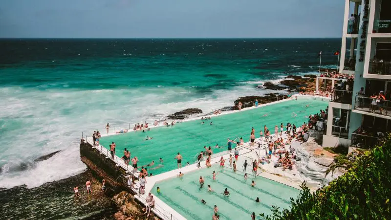 Travellers relax in scenic oceanfront pools beside rugged rocks—experience The Great Escape Australia 28-Day Semi-Guided Adventure.