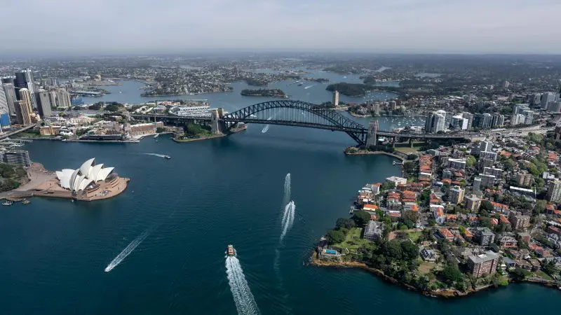 Stunning aerial view of Sydney Harbour featuring the iconic Opera House, city skyline, and boats—Great Escape Australia 28 Day Tour.
