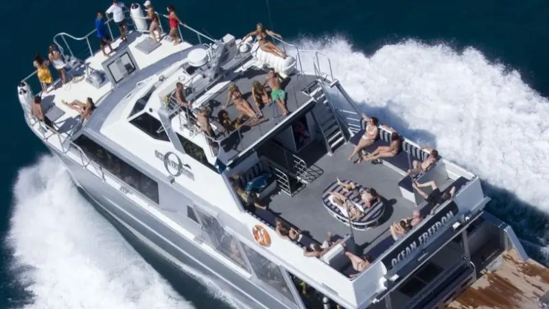 Travellers sunbathe on a luxury yacht with The Great Escape Australia 28 Day Semi-Guided cruise, leaving a sparkling white wake behind.