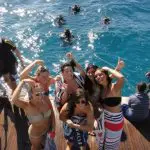 Smiling friends in swimwear enjoy a sun-filled boat ride on The Great Escape Australia 28 Day Semi-Guided tour adventure.
