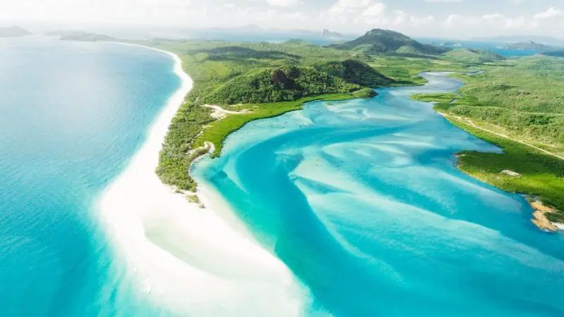 Stunning aerial shot of pristine white sands and turquoise waters on The Great Escape Australia 28 Day Semi Guided tour, sunny skies overhead.