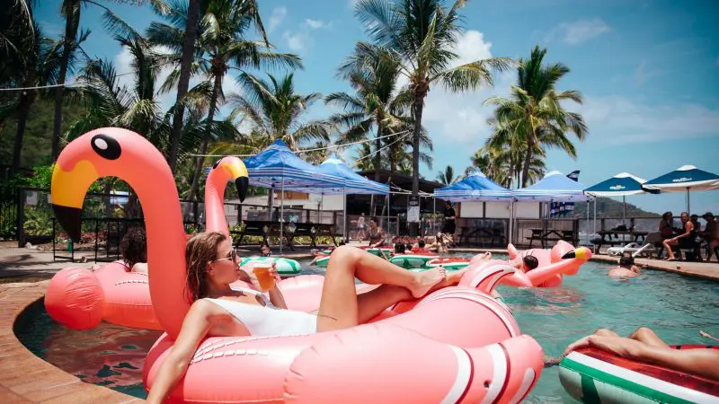Woman lounging on a vibrant pink flamingo float at The Great Escape 21 Day Semi-Guided Group Tour from Brisbane to Cairns, Australia.