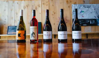 A selection of five premium wine bottles arranged on a rustic wooden table, ideal for an unforgettable wine tasting session.