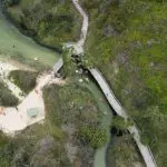 Stunning aerial view of Kgari 2 Day Tour’s winding boardwalk crossing a stream, guiding visitors to Noosa’s pristine sandy beach.