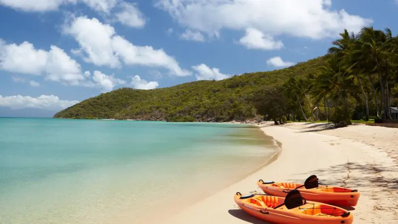 Vibrant orange kayaks on pristine white sand at a tropical beach, ideal for the ultimate 3 Day Daintree Cape Tribulation tour.