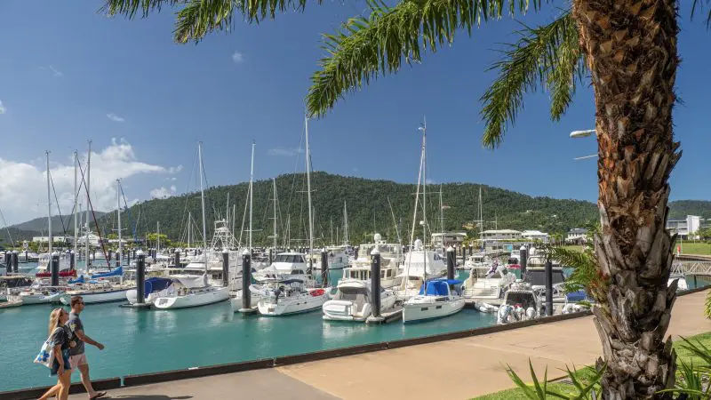 Travellers enjoy a scenic marina stroll past luxury yachts on the 14 Day Sydney to Cairns Tour, featuring Fraser Island and Whitsundays.
