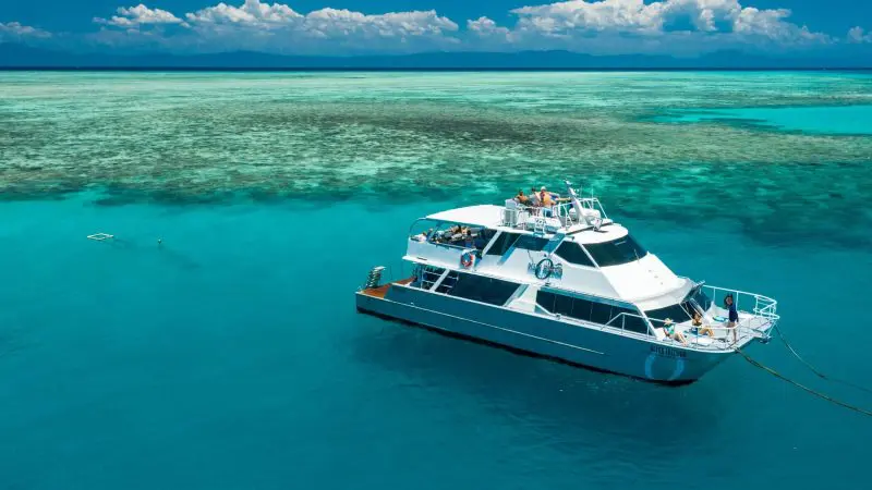 Luxurious white yacht anchored by a vibrant coral reef during the 14-Day Sydney to Cairns Fraser Island & Whitsundays Comfort Tour.
