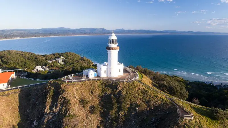 Stunning white lighthouse on a lush grassy cliff, featured on the 14-Day Sydney to Cairns and Fraser Island Whitsundays Tour.
