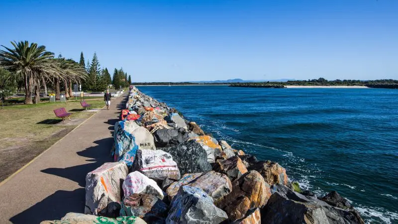 Scenic seafront walkway with colourful painted rocks on the 14 Day Sydney to Cairns, Fraser Island & Whitsundays Comfort Tour route.