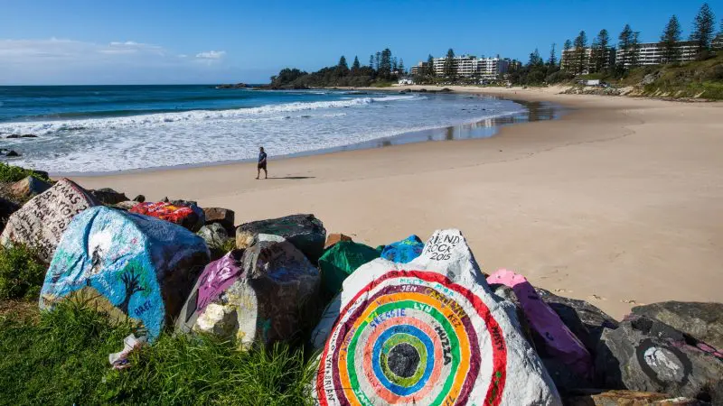 Vividly painted rocks line a sandy beach on the 8 Day Sydney to Brisbane With Fraser Island Comfort Tour, Australia coastal scenery.