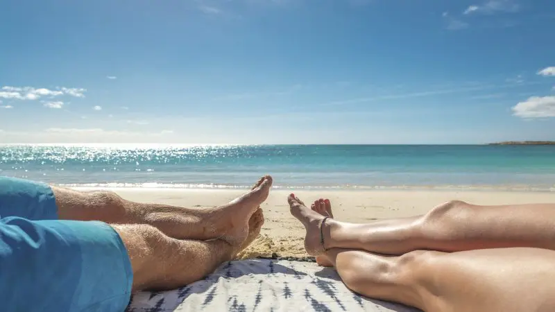 Two people relax on a pristine beach, envisioning the ultimate 8 Day Perth to Exmouth Comfort Tour and Ningaloo Reef wonders.