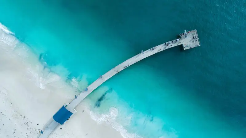 Stunning aerial view of a scenic curved pier over vibrant turquoise waters on the 8 Day Perth to Exmouth Comfort Tour coastline.