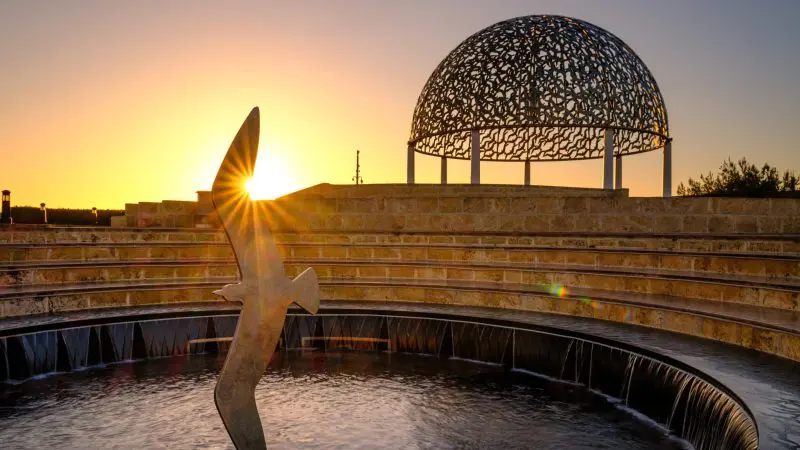 Stunning metal bird sculpture in fountain, domed pavilion at sunset—captures the essence of Perth to Exmouth coastal tour highlights.