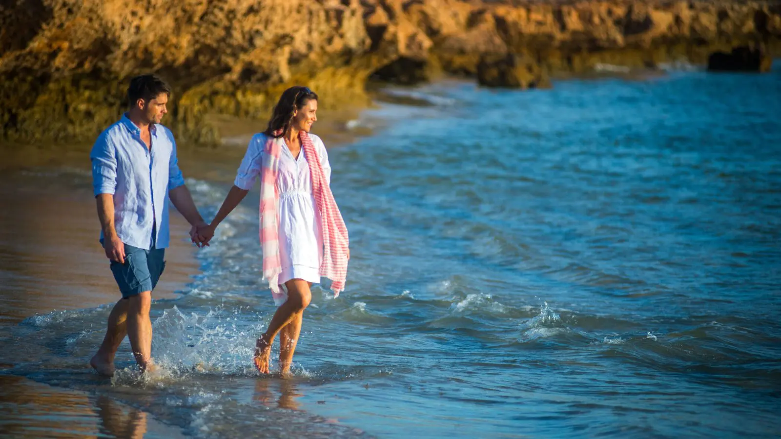 A joyful couple walks hand in hand along the pristine Perth to Exmouth coast, enjoying scenic views on their 8 Day Comfort Tour.