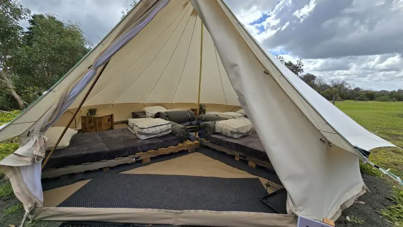 Spacious canvas tent with two made beds overlooks a lush grassy field—perfect base camp for the Kangaroo Island 2-Day Wildlife Tour.