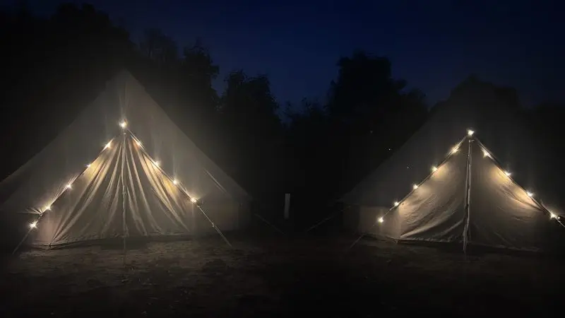 Glowing tents with fairy lights on Kangaroo Island at night, perfect for a 2-day wildlife adventure beneath a vibrant blue sky.