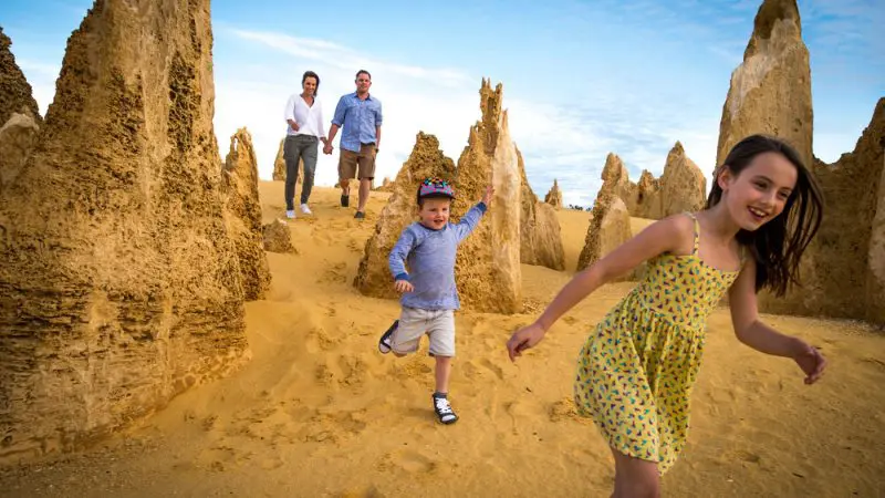 A family enjoys the famous Pinnacles Desert’s striking yellow rock formations on a 1 Day Lobster Lavender Tour from Perth, under a bright blue sky.