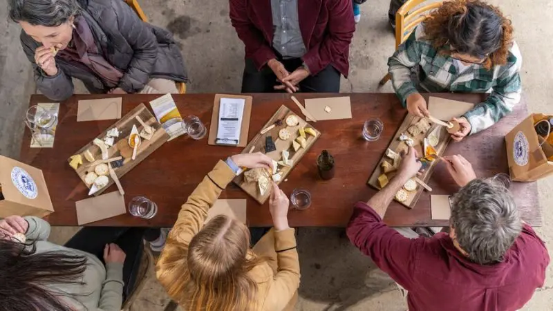 Aerial view of six people enjoying cheese and crackers during a 1 Day Hunter Valley Wine Tour, showcasing winery dining experience.