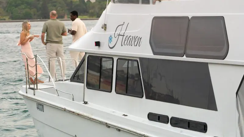 Three friends converse on Heaven on the Water’s deck during a Sydney Harbour Golden Glow Sunset Cruise, city skyline in the background.