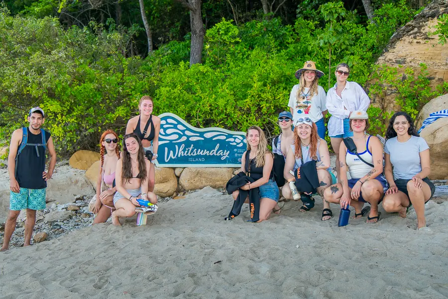 tour group gathered around whitehaven beach sign