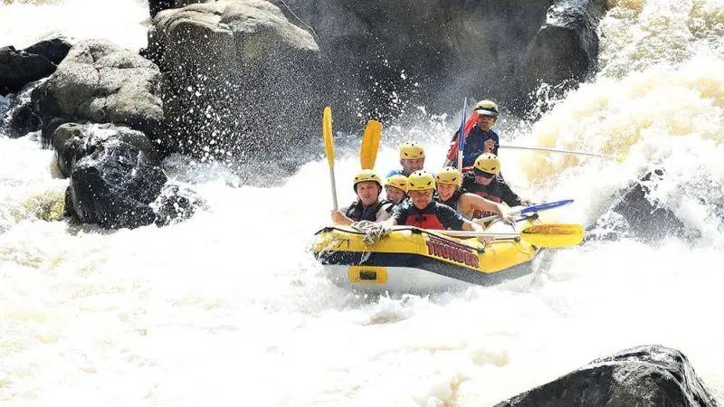 Six helmeted adventurers navigate intense Barron River rapids on a thrilling Half Day White Water Rafting Raging Thunder tour.