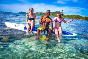 Image of friends laughing and having fun and sitting on a padel board in the ocean in Fiji