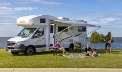 Family sitting on grass outside Apollo Euro Deluxe. The beach is behind them.