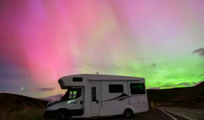 RV parked with southern lights green and pink above