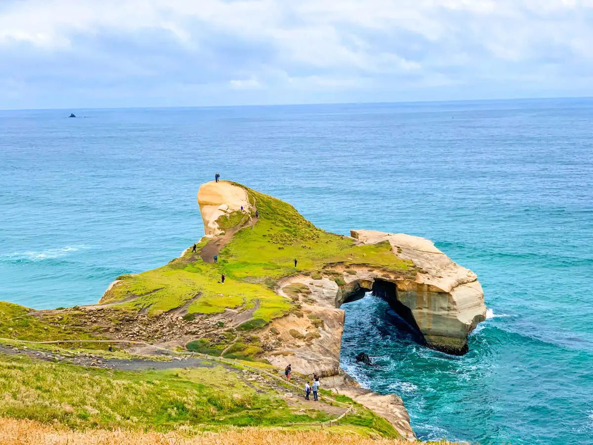 Rock formation over blue water that creates a tunnel shape.