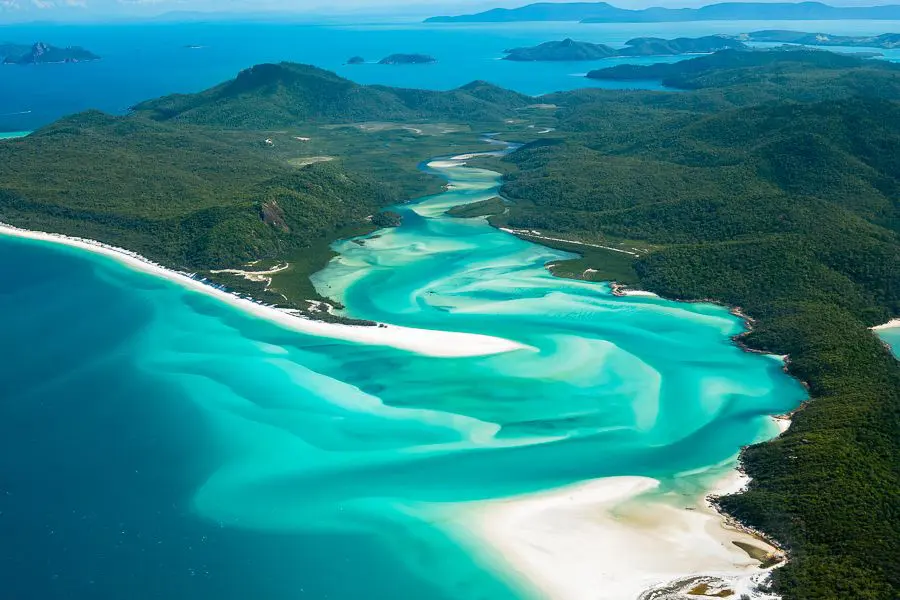 Whitsundays from a birds eye view. Green islands in bright blue ocean water with swirling white sand and blue water mix together