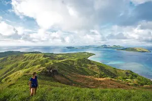 Image of backapcker hiking a beautiful mountain in Fiji whilst admiring the stunning views overlooking the Ocean