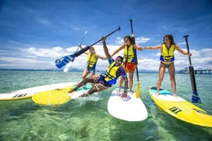 Picture of a young group of friends paddle boarding in Fiji during their Fiji activity package