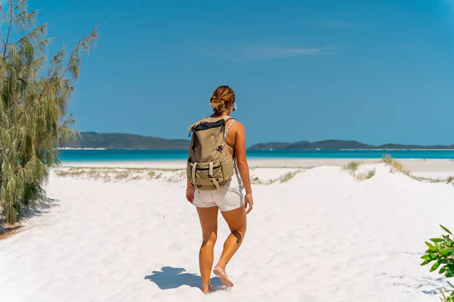 girl with backpack walking on whitehaven beach whitsundays
