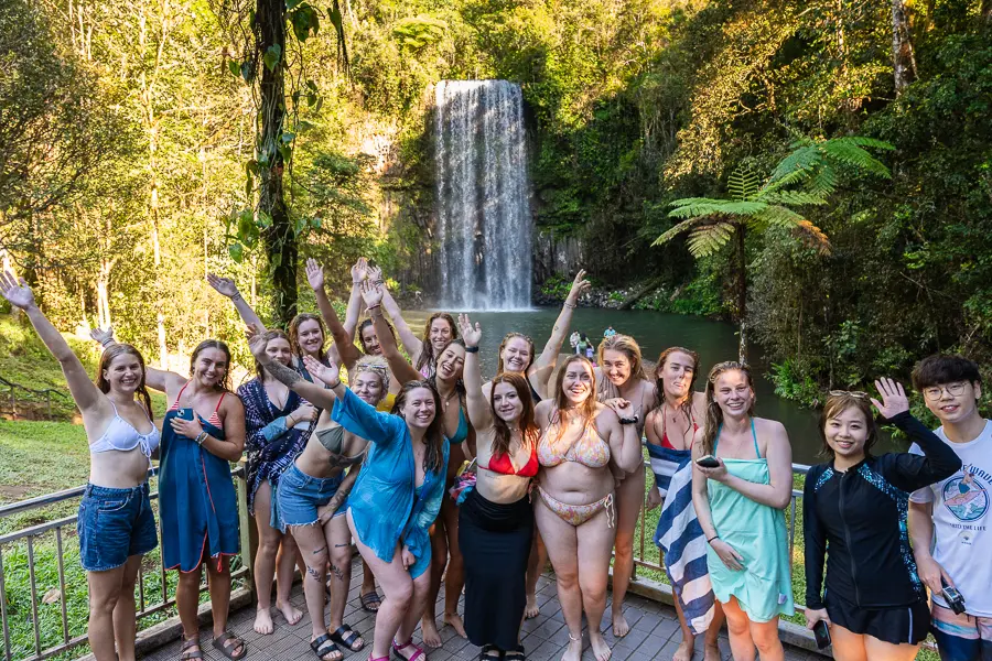 Tour group posing in front of waterfalls near cairns australia