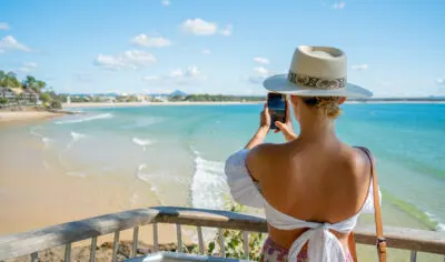 A woman taking a photo of the main beach in Noosa.