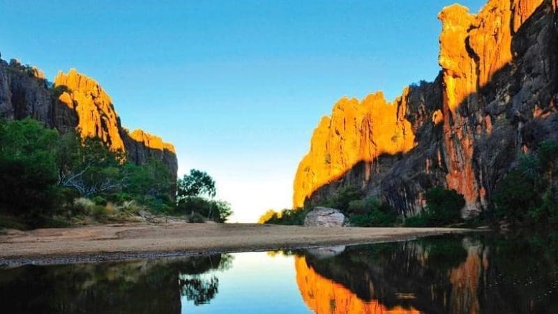 Sunlit cliffs mirrored in a tranquil river on the 10 Day Broome to Darwin 4WD Kimberley Adventure—breathtaking Australian outback scenery.