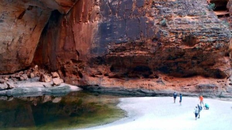 Travellers trek across pristine white sand beside a clear, shallow canyon pool on a 10 Day Darwin to Broome 4WD Adventure tour.