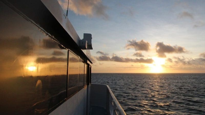 Stunning sunset view over the Great Barrier Reef sea from a boat window during a 3 Day 2 Night snorkelling tour adventure.