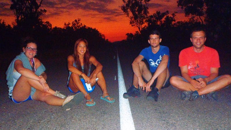 Explore the 3 Day 4WD Kakadu Adventure Tour: four travellers unwind on a scenic sunset road, Jun–Sept. Experience Kakadu's beauty.