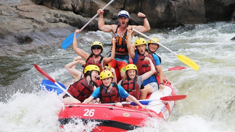 Thrill-seekers in helmets and life jackets smile on a Barron River rafting adventure, setting off from Port Douglas, ready for excitement.
